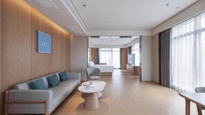 A modern hotel room with a sofa, a round coffee table, a bed, and a TV. - Ji Hotel (Wuhan)