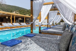 A poolside area with lounge chairs and a pool. - Skiathos Thalassa (Skiathos)