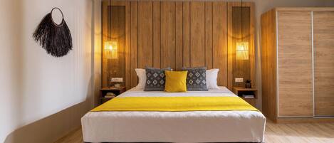 A modern bedroom with a large bed, wooden panel wall, bedside lamps, and a wardrobe.