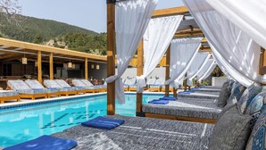 A poolside area with lounge chairs and a pool. - Skiathos Thalassa (Skiathos)