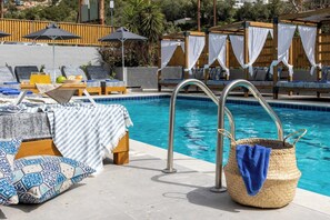A poolside area with lounge chairs, umbrellas, and a pool with metal ladders. - Skiathos Thalassa (Skiathos)