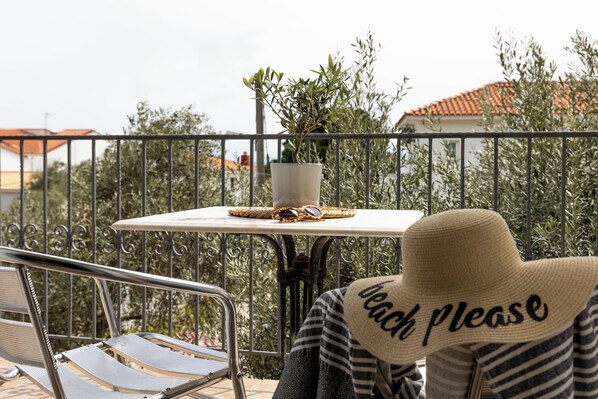A balcony with a table, a potted plant, and a chair.