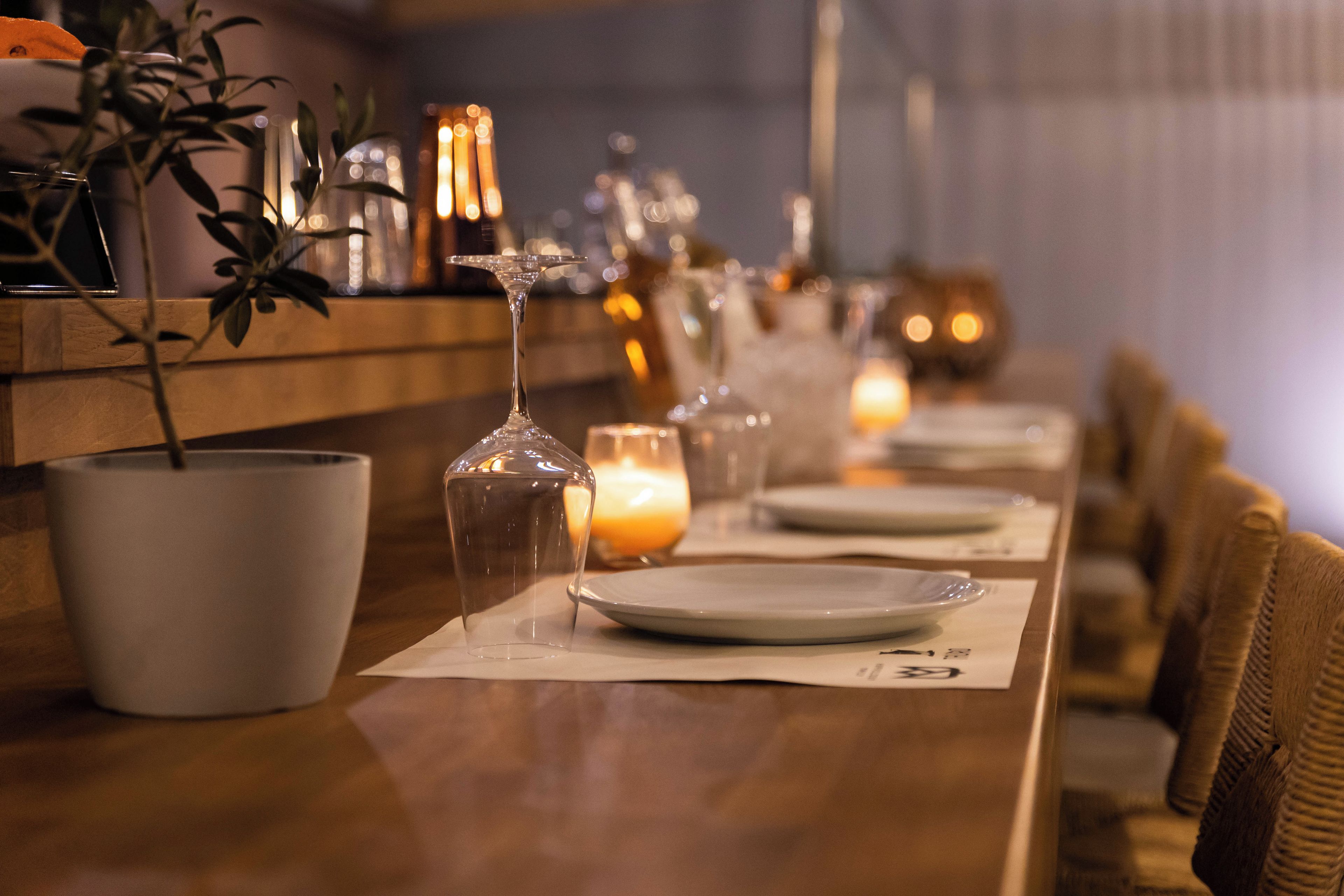 A restaurant setting with a long table, candles, and glasses.