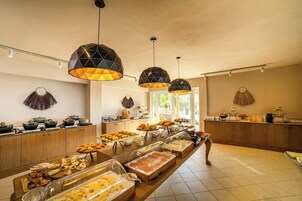Una mesa de buffet con diversos alimentos, armarios de madera y lámparas colgantes.