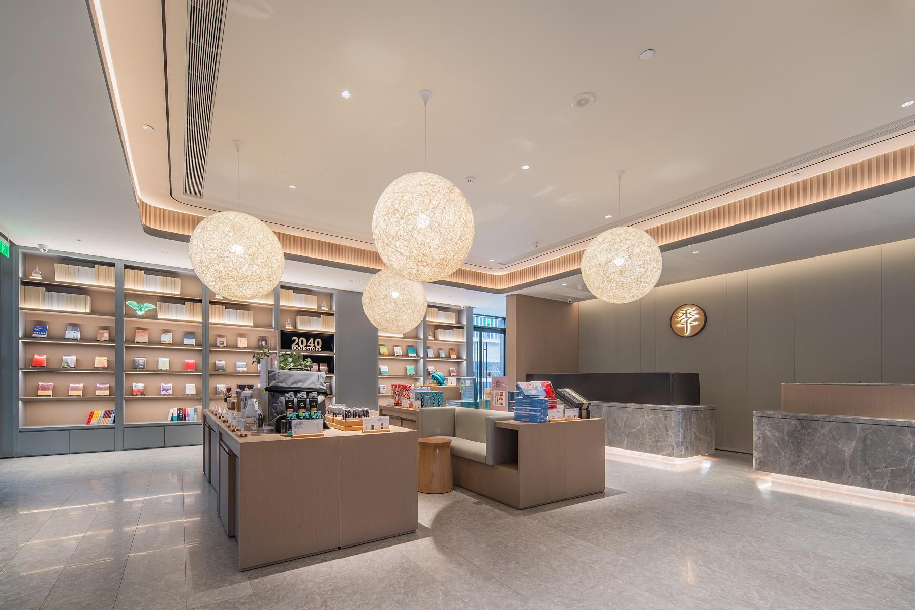 A modern bookstore interior with large spherical chandeliers, a reception desk, and neatly organized shelves.