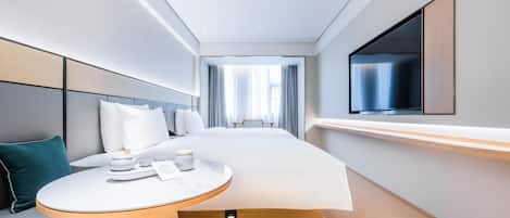 A modern hotel room with a bed, bedside table, TV, and a view of the hallway.