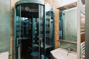 Un baño con ducha envuelta en vidrio, un lavabo y un espejo.