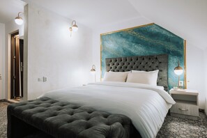 Un dormitorio con cabecera capitonada, una cama grande, mesitas de noche y un aplique de pared.
