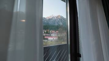 Une fenêtre donnant sur une montagne et des bâtiments.