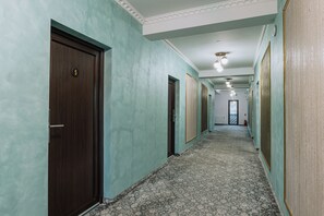 A hallway with doors, patterned carpet, and a ceiling with recessed lighting. - Suru Hotel (Busteni)