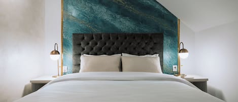 A modern bedroom with a tufted headboard, a large bed, and two bedside lamps.