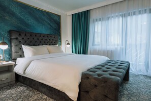 A large bed with a tufted headboard, a bedside lamp, and a patterned carpet. - Suru Hotel (Busteni)