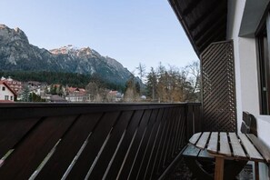 A balcony with a wooden railing, a wooden bench, and a mountain view in the background. - Suru Hotel (Busteni)