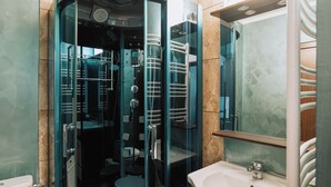Uma casa de banho moderna com chuveiro de vidro, uma pia e um espelho.
