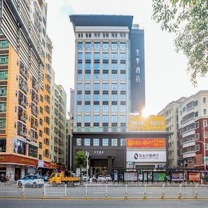 Un hotel de varios pisos con una entrada destacada, rodeado de otros edificios y una calle con mucho tráfico.