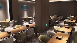 Un salón de conferencias moderno con varias mesas y sillas, equipado con iluminación integrada y un pilar central.