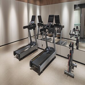 A modern gym with stationary bikes, treadmills, and a mirrored wall. - Ji Hotel (Shenzhen)