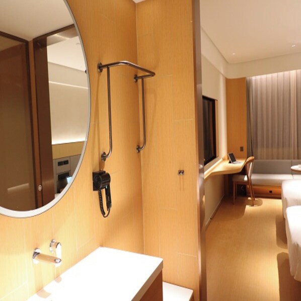 A hotel room with a wooden wall, a round mirror, a sink, a shower area, a bed, and a window with curtains. - Ji Hotel (Shenzhen)