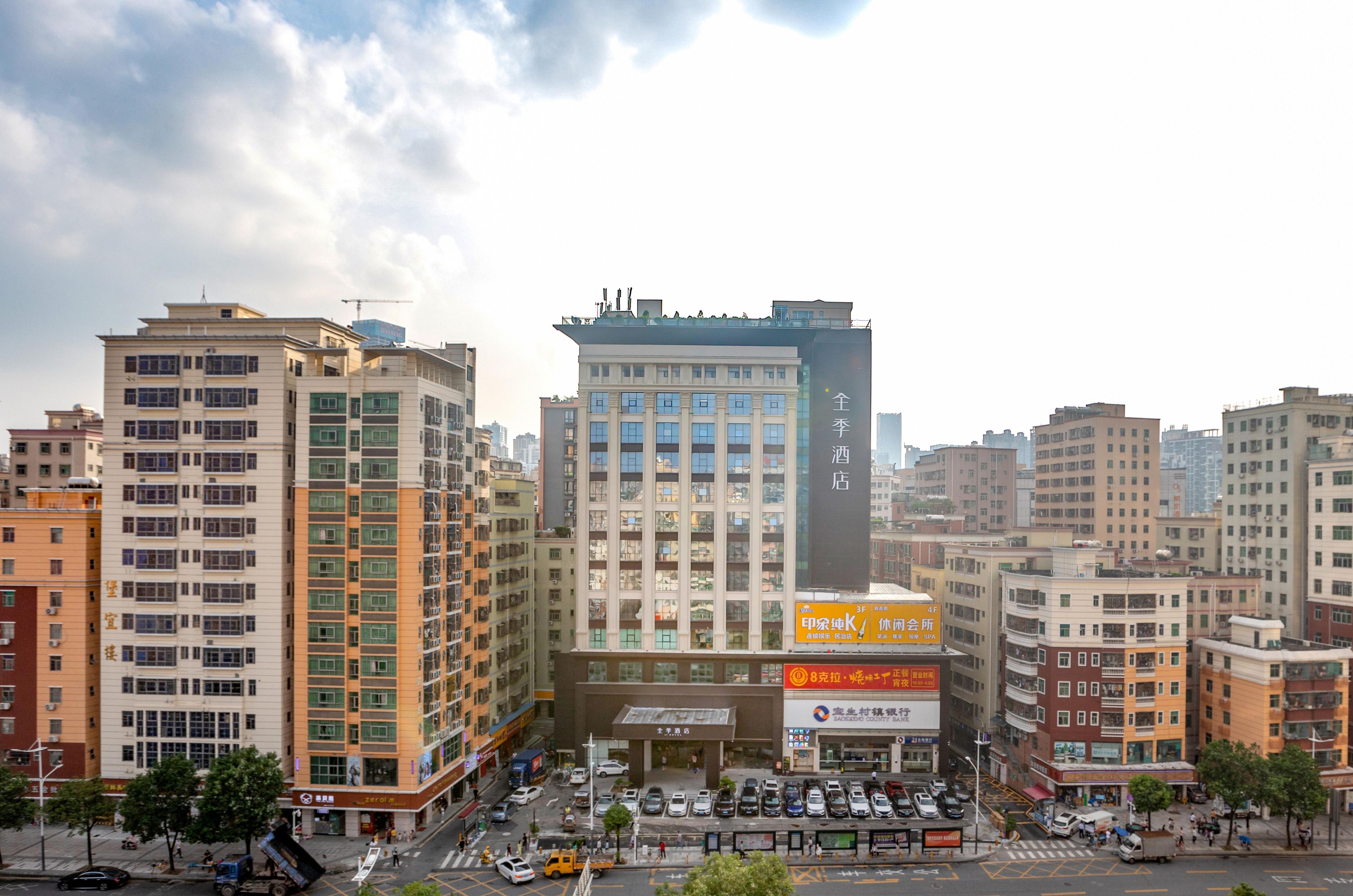A multi-story hotel with a central entrance, surrounded by other buildings.