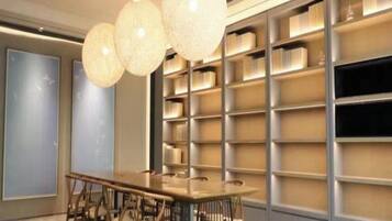 A modern meeting room with a long table, chairs, and a bookshelf.