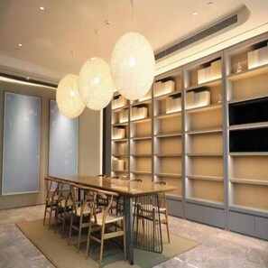 A modern meeting room with a long table, chairs, and a bookshelf. - Ji Hotel (Shenzhen)