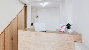 A reception desk with a laptop, two potted plants, and a sign. - OYO 90756 Melasti Hills Room & Cafe (Ungasan)