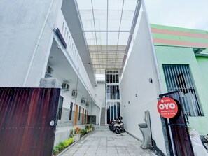 A building entrance with a covered walkway, a parked motorcycle, and a sign for 'OYO Melasti Hills Room & Cafe'. - OYO 90756 Melasti Hills Room & Cafe (Ungasan)