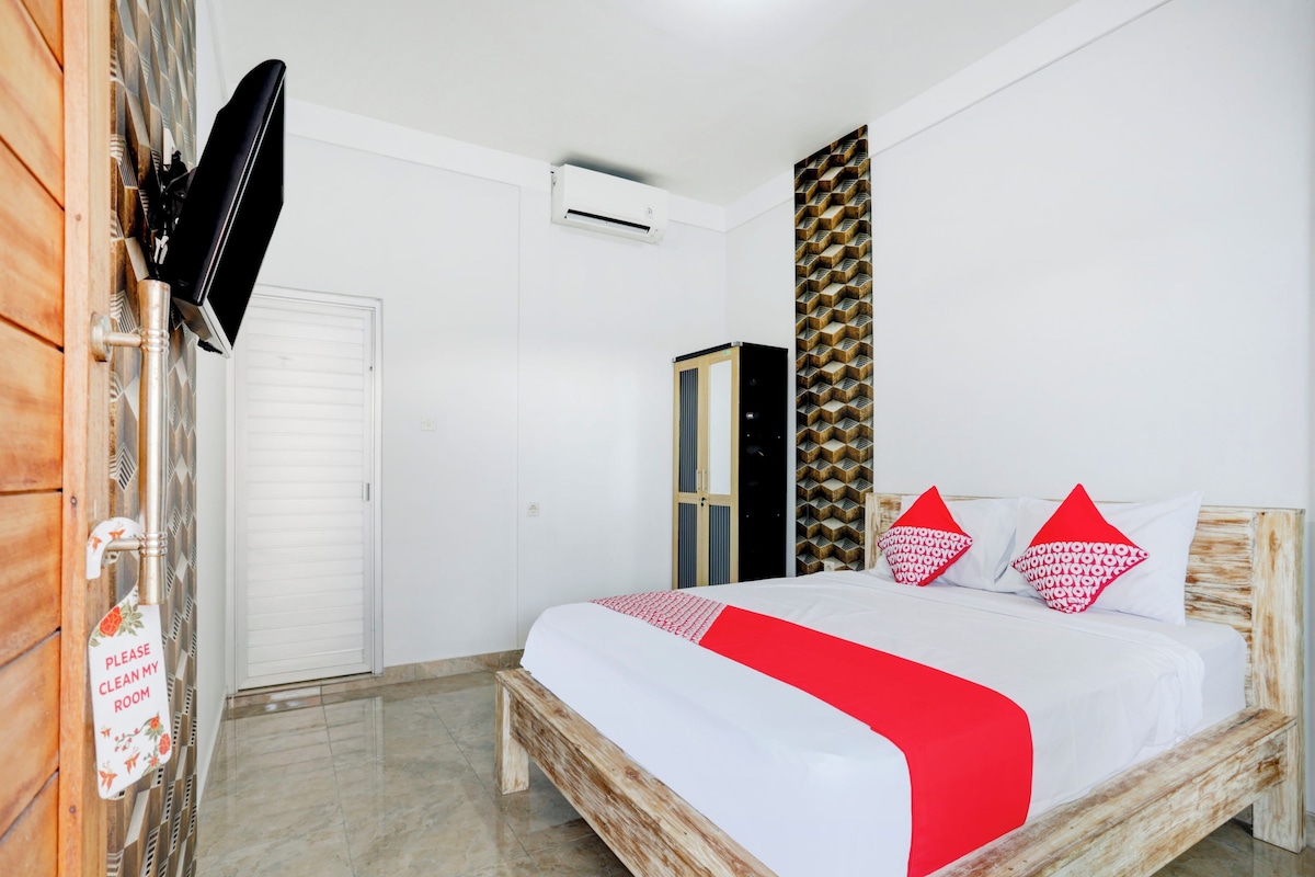 A bedroom with a bed, a wardrobe, a television, and a wall-mounted air conditioner.