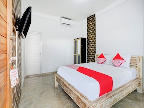 A bedroom with a bed, a wardrobe, a television, and a wall-mounted air conditioner. - OYO 90756 Melasti Hills Room & Cafe (Ungasan)
