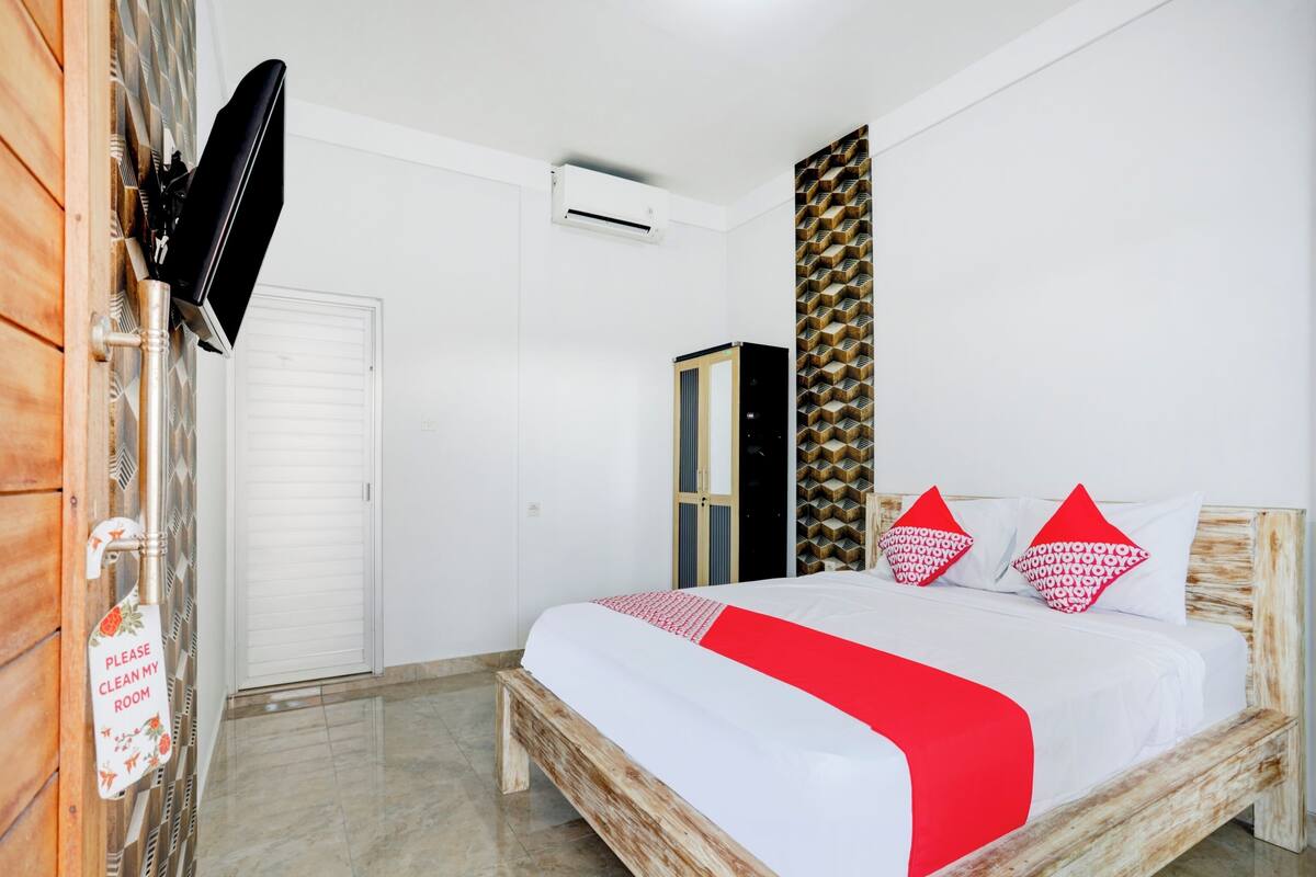 Une chambre à coucher comprenant un lit, une armoire, un téléviseur et un climatiseur fixé au mur.