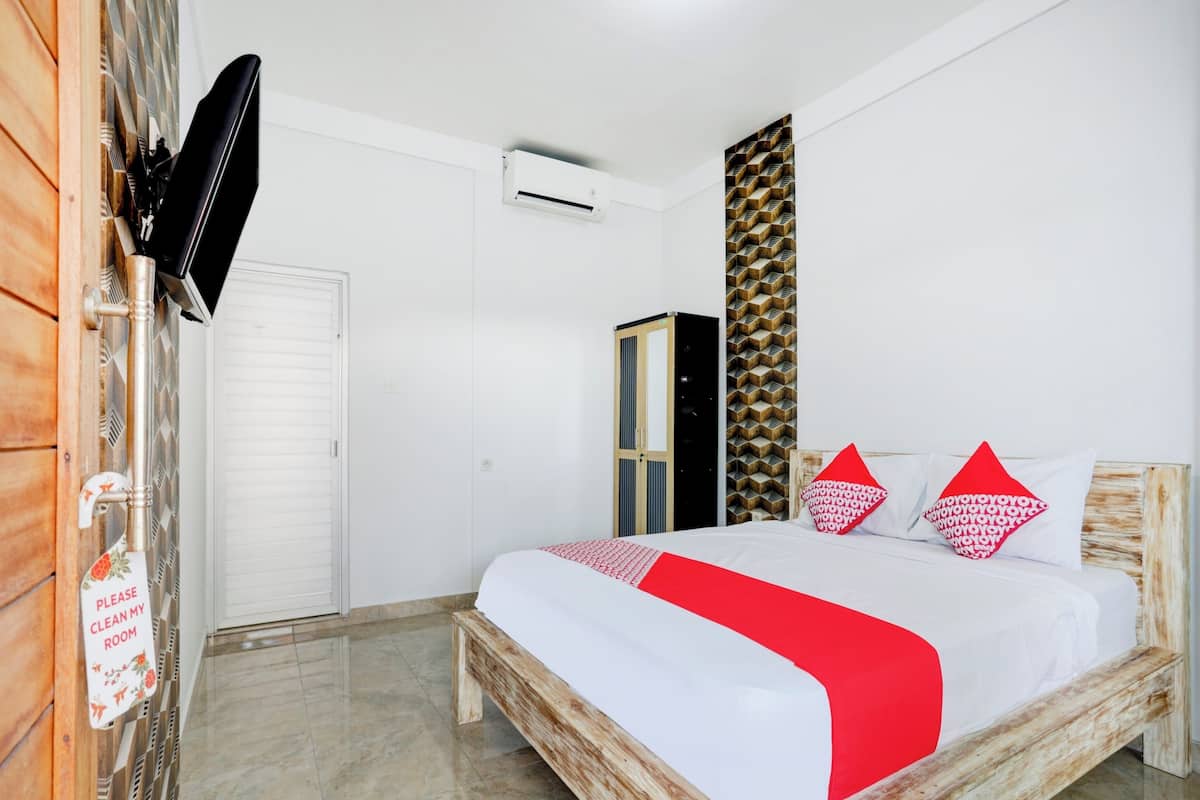A bedroom with a bed, a wardrobe, a television, and a wall-mounted air conditioner.