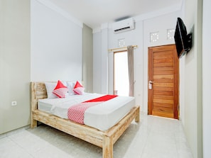 A bedroom with a wooden bed, white walls, a wooden door, and a mounted TV. - OYO 90756 Melasti Hills Room & Cafe (Ungasan)