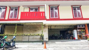 Un edificio con techo de tejas rojas, varias ventanas y un escaparate con una pizarra de menú.