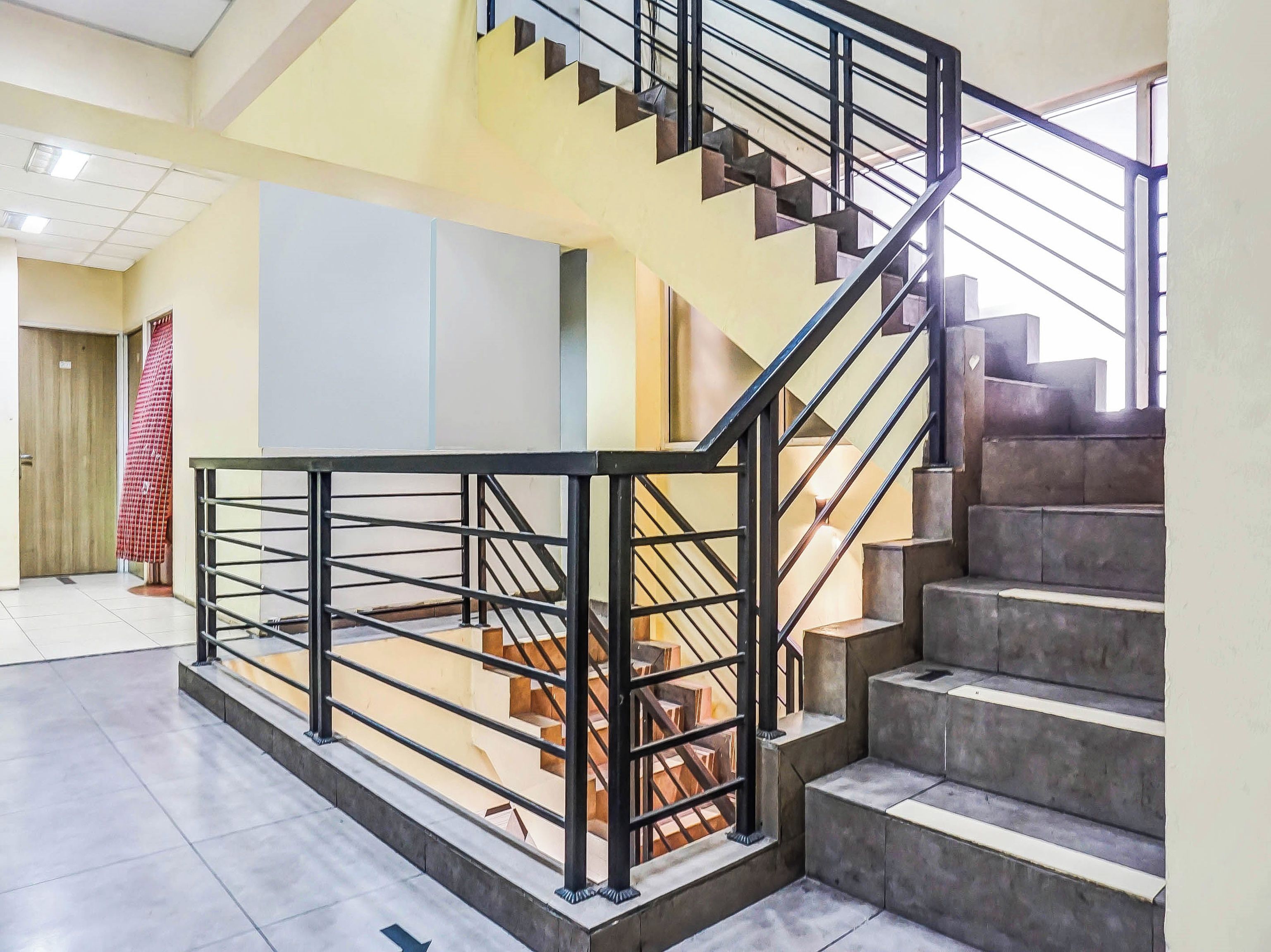 A modern staircase with metal railings, a tiled floor, and a view of the interior space.