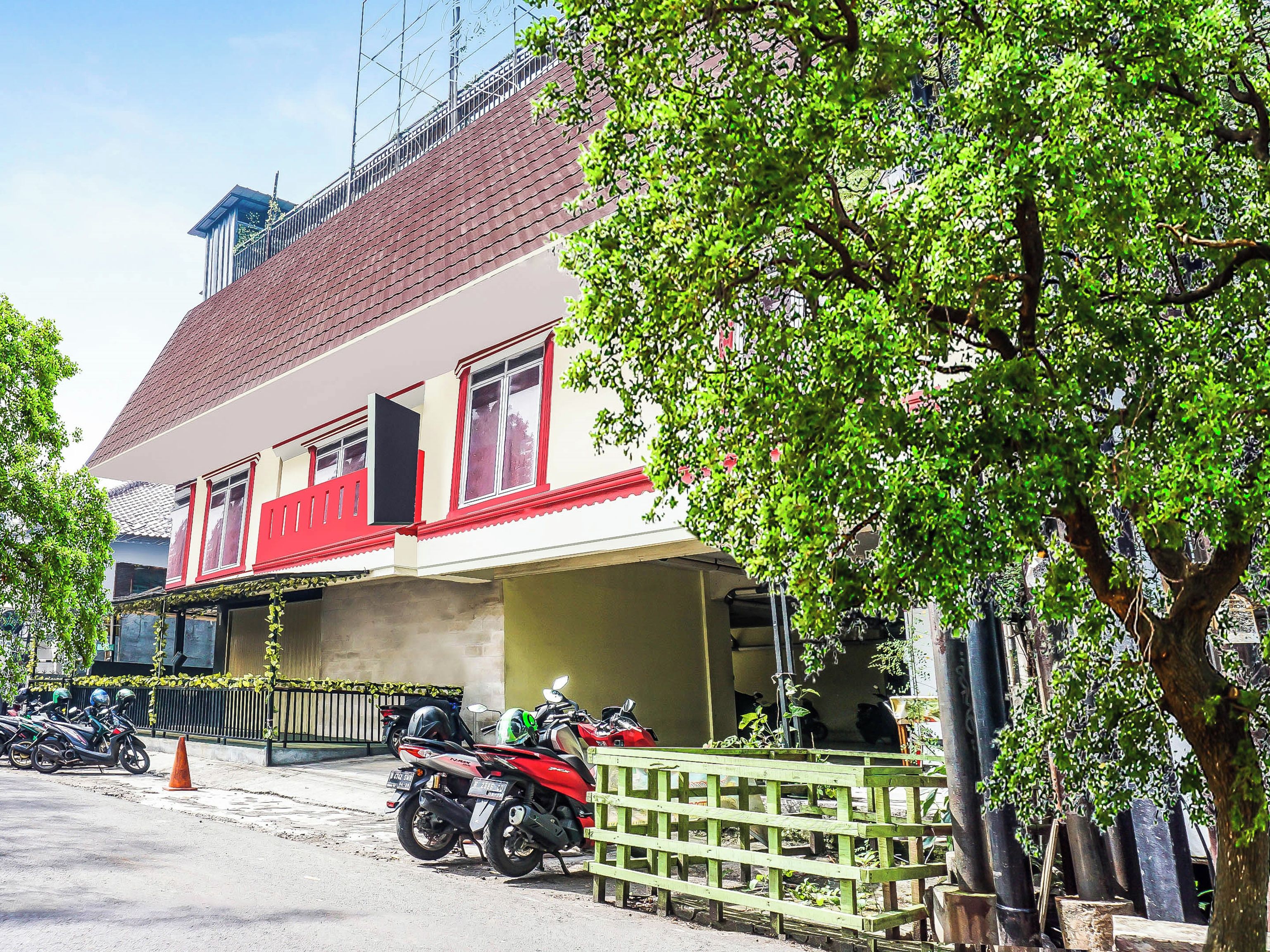 A building with a red and white facade, a balcony, and a parked motorcycle.