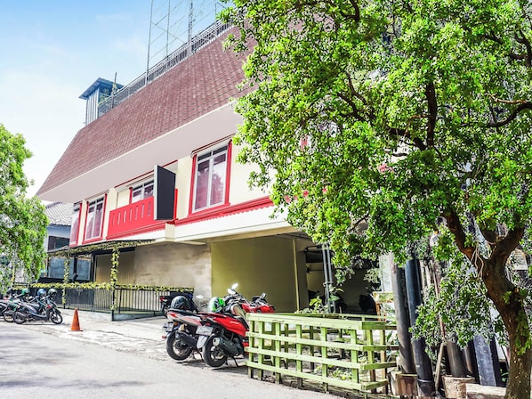 Un edificio con fachada roja y blanca, un balcón y una motocicleta estacionada.