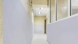 Un pasillo con paredes blancas, suelo de baldosas y una puerta al final.