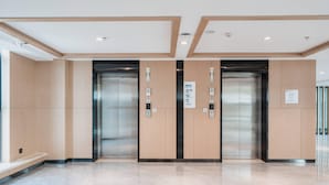 A modern elevator area with two elevators, marble flooring, and wooden paneling.