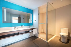 A modern bathroom with a large mirror, a sink, and a toilet.
