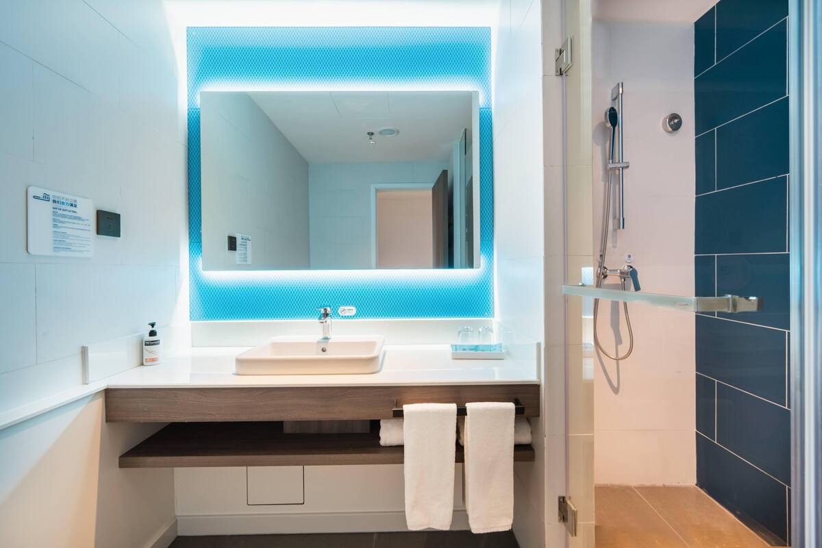 A modern bathroom with a large mirror, a sink, and a shower.