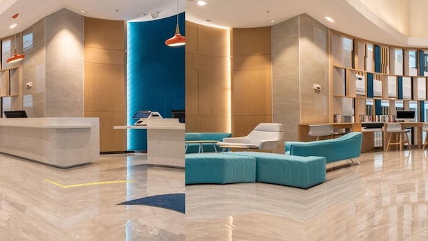 A spacious lobby with a reception desk, seating area, and a large wall with a unique design.