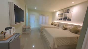 A hotel room with two beds, a TV, a kitchenette, and a bathroom.