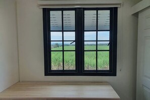 A room with a large window overlooking a green field. - Aob-oun Glamping by Zuzu (Pak Chong)