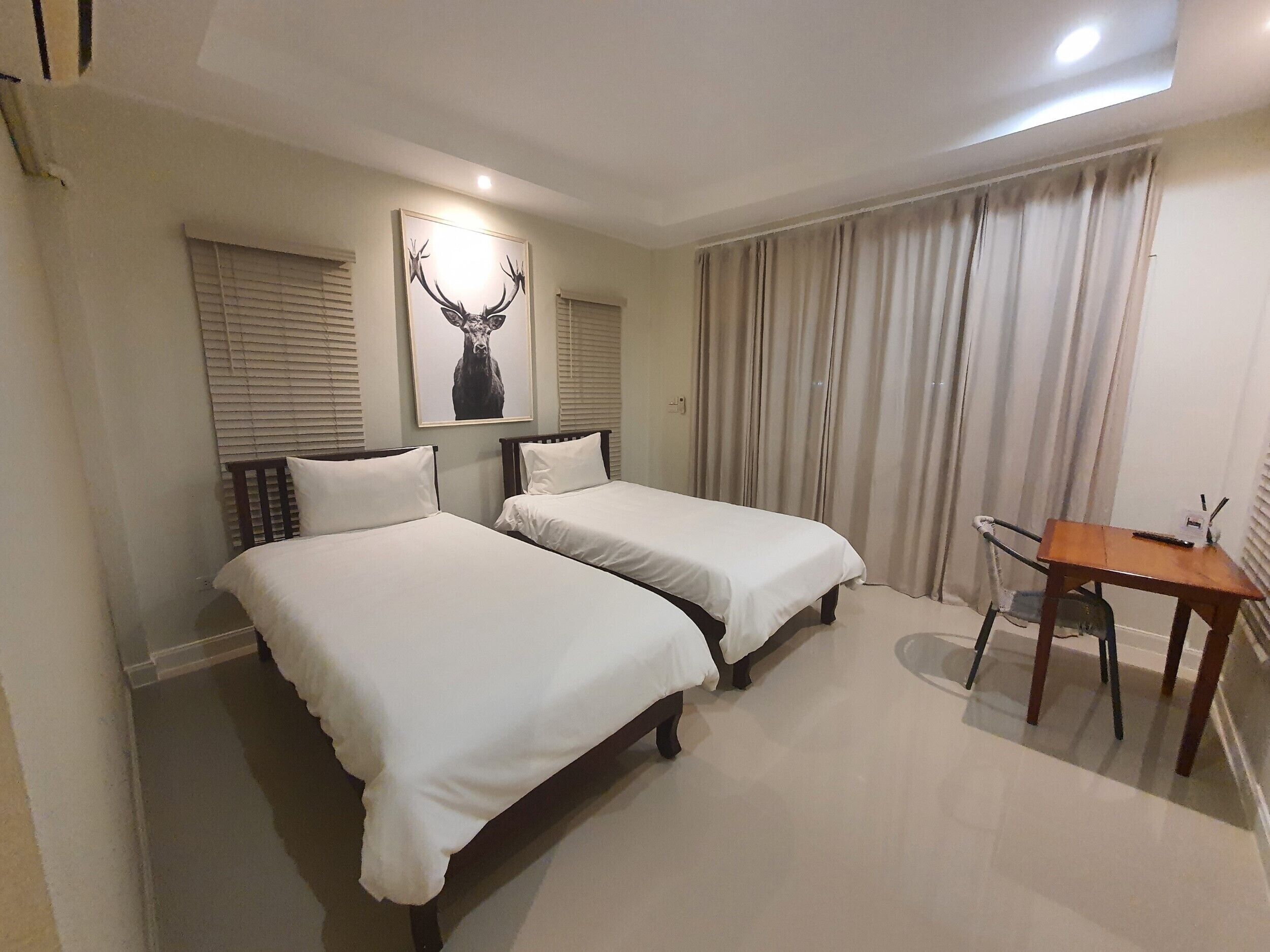 Ein Hotelzimmer mit zwei Betten, einem Schreibtisch und einem Bild eines Rehs.
