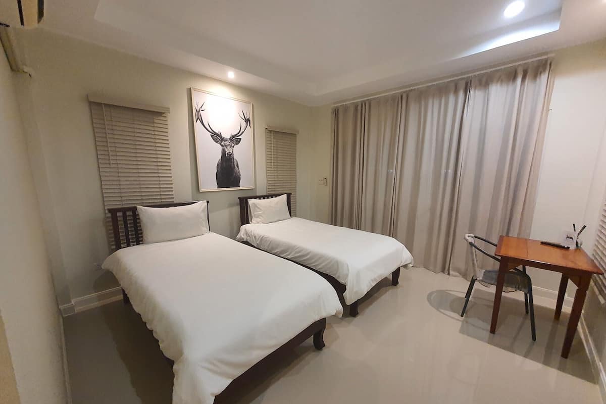 Habitación de hotel con dos camas, un escritorio y un cuadro de un ciervo.