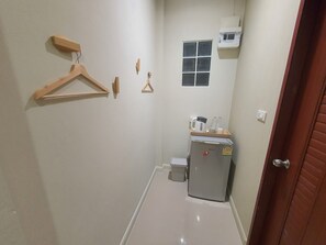 Un pasillo estrecho con un refrigerador, una ventana pequeña y una puerta.