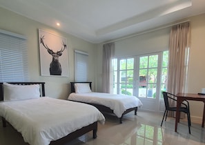 Habitación de hotel con dos camas, un escritorio y un ventanal grande con cortinas.