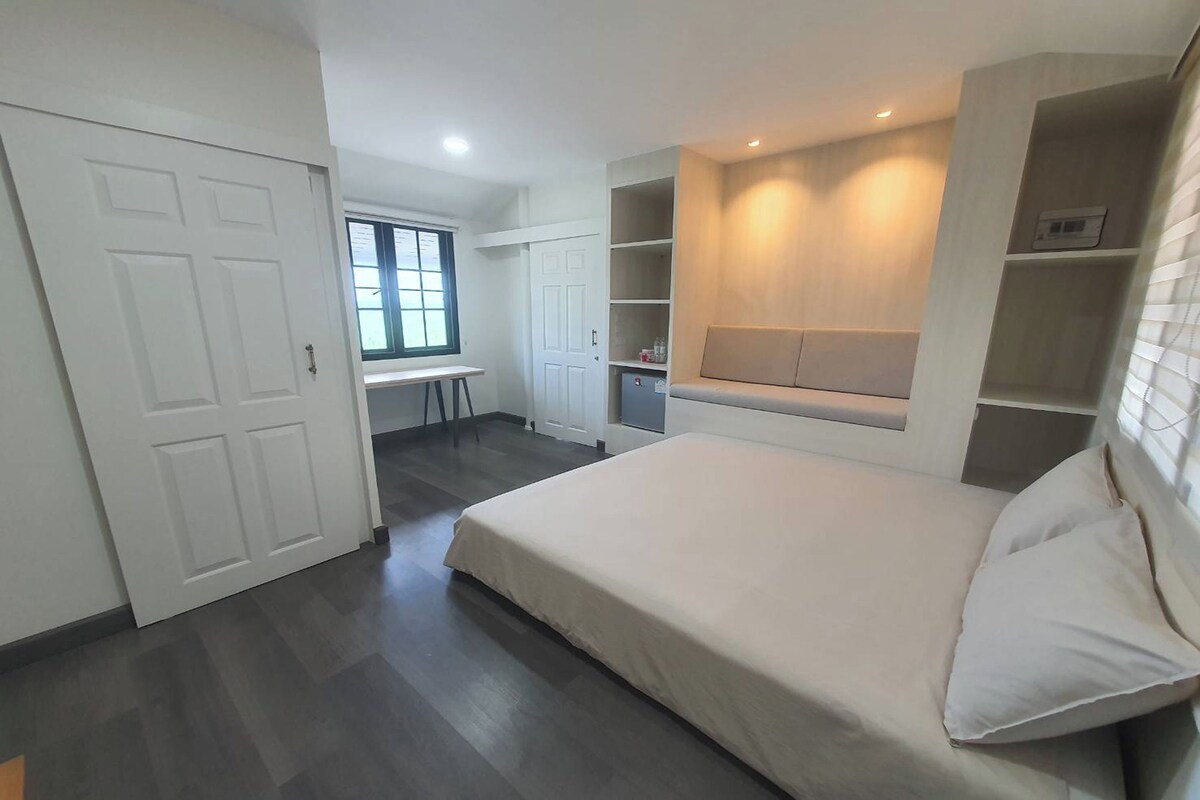 Une chambre à coucher comprenant un lit, des étagères intégrées, un bureau et une fenêtre.