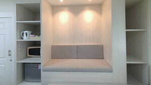 Habitación pequeña con asientos integrados, estanterías y microondas.