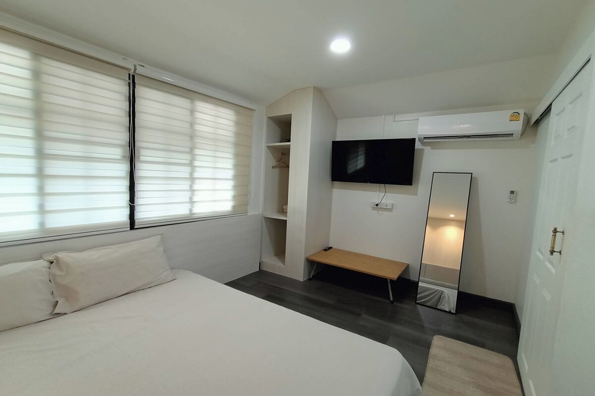 A bedroom with a bed, a TV, a mirror, and a wardrobe.